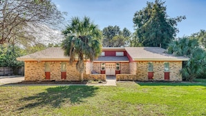A single-story brick house with a red roof, a front porch, and a small front yard. - Pet-Friendly Family Getaway Near Two Beaches (Gulf Breeze)