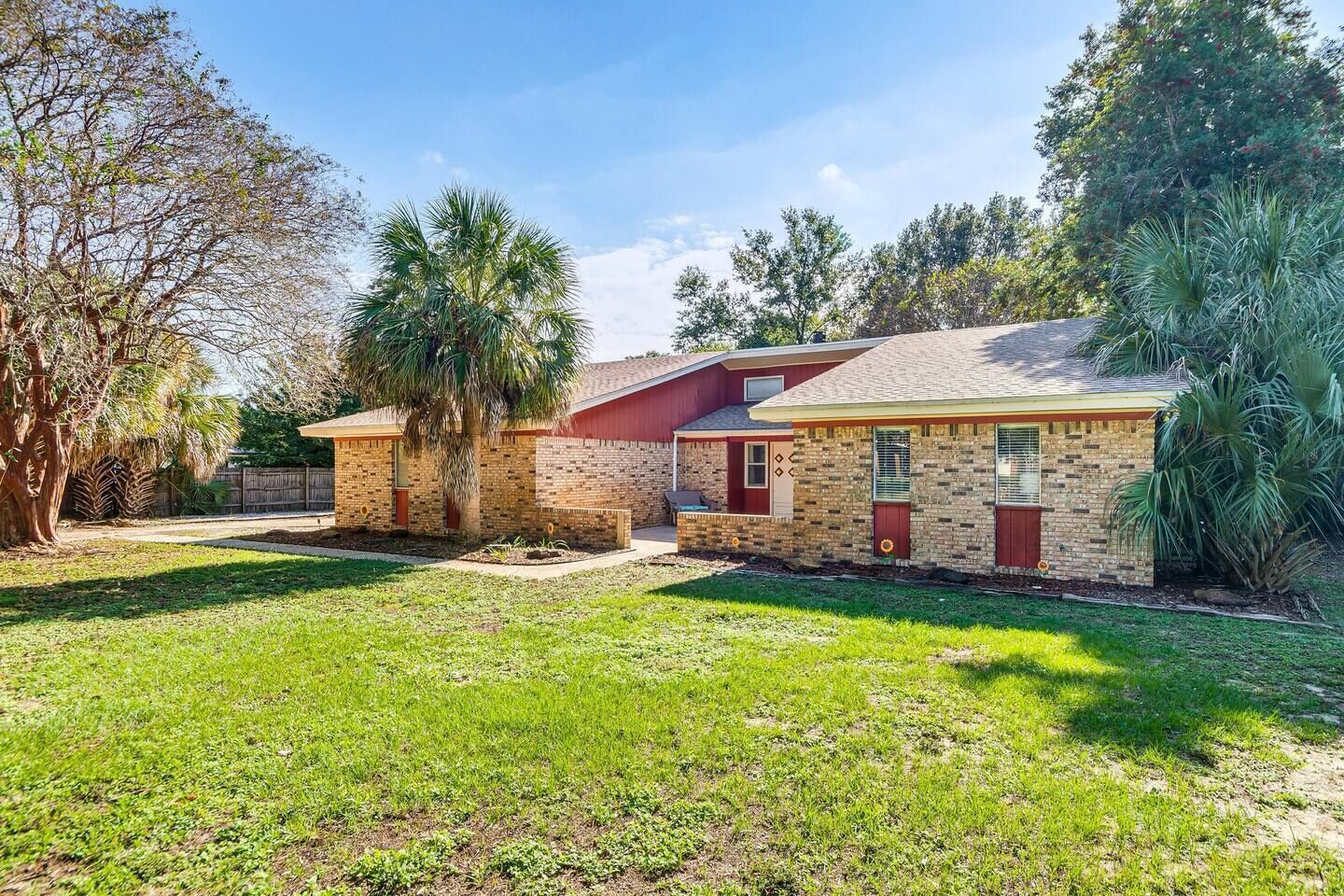 A residential property with a brick house, a small attached garage, and a well-maintained lawn.