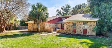 A residential property with a brick house, a small attached garage, and a well-maintained lawn.