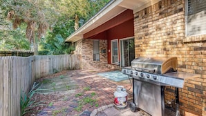 A backyard with a brick patio, a barbecue grill, and a propane tank. - Pet-Friendly Family Getaway Near Two Beaches (Gulf Breeze)
