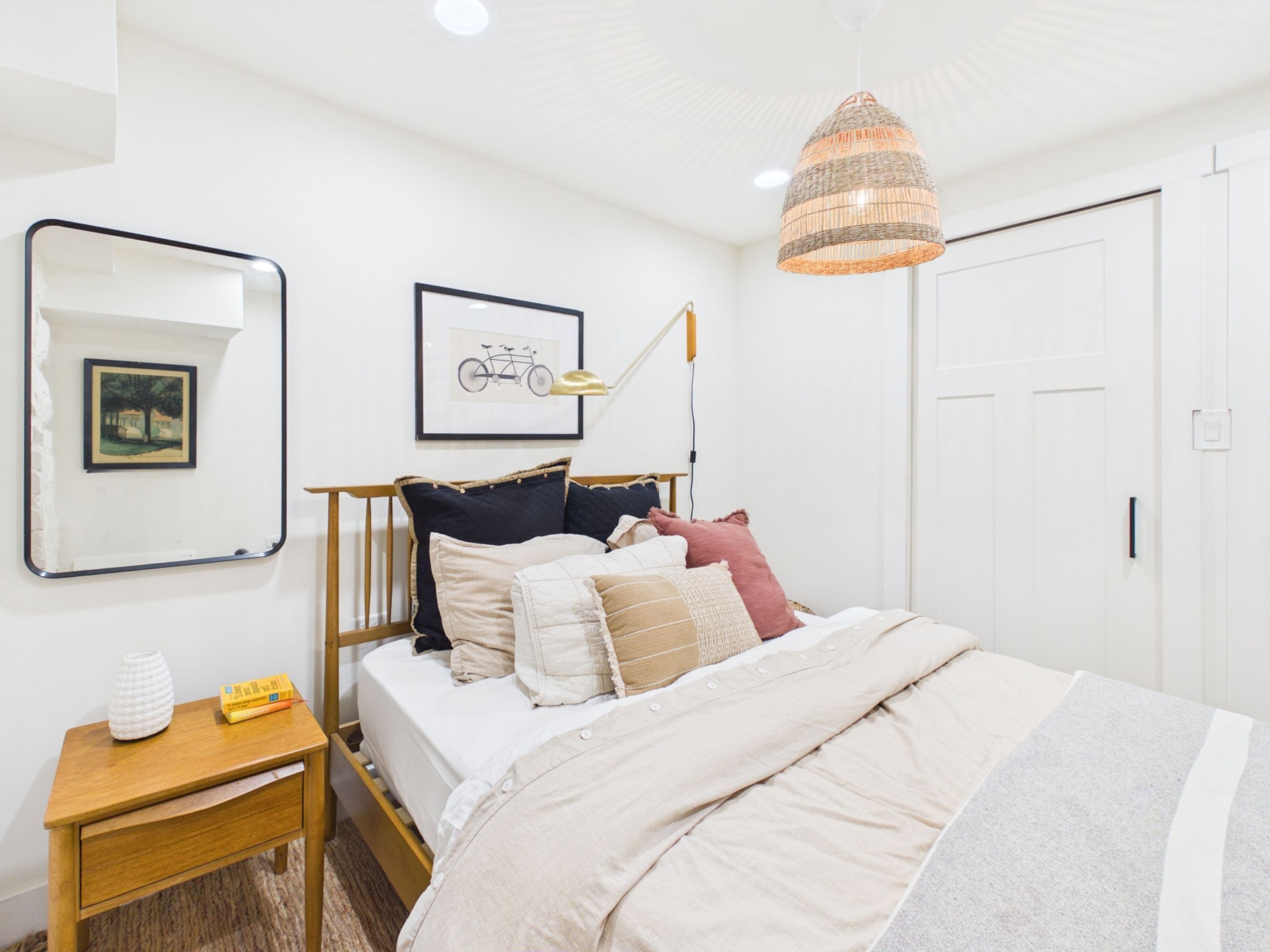 A bedroom with a bed, bedside table, lamp, and framed pictures on the wall.