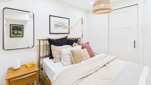 Ett sovrum med en säng, ett sängbord, en lampa och inramade bilder på väggen.