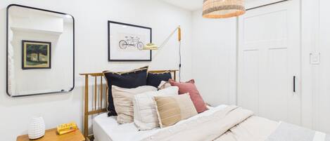 A bedroom with a bed, bedside table, lamp, and framed pictures on the wall.