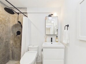 A bathroom with a white sink, a mirror, a toilet, and a shower area. - Cozy 1 Bedroom Apartment 20 Minutes from Downtown Chicago (Chicago)