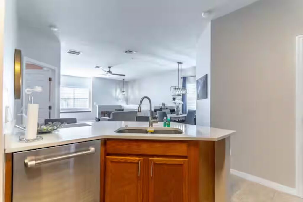 A modern kitchen with a built-in dishwasher, wooden cabinets, and a stainless steel sink.