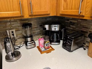 Eine Küche mit Holzausstattung, einer Kaffeemaschine, einem Toaster, einem Mixer und einem Kaffee-Pod-Halter.