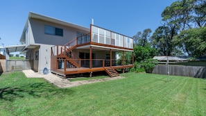 Ein zweistöckiges Haus mit einer Holzterrasse und einem überdachten Außenbereich.