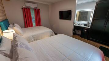 Een hotelkamer met twee bedden, een televisie, een minibar en een badkamer met een spiegel.