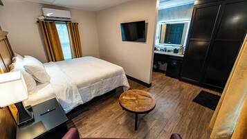 Ein Hotelzimmer mit Bett, Schreibtisch, Stuhl, kleinem Tisch, Fernseher und einer Küchenzeile.