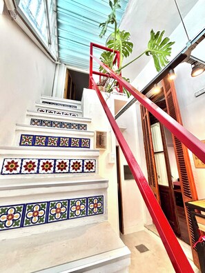 Una escalera con baldosas de colores y barandilla roja.