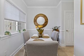 A dining area with a white table, grey upholstered chairs, a decorative mirror, and a vase with yellow flowers. - 2BR 2Bath Intracoastal waterfront condo in golf course community Dog friendly!  (Myrtle Beach)