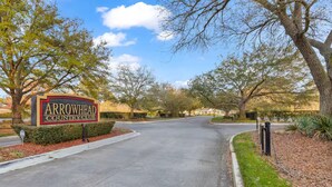 Segnaletica per l'Arrowhead Country Club, con un viale alberato che conduce a una zona residenziale.