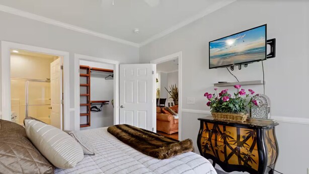 Una camera da letto con un letto, una televisione a muro, un armadio e una finestra con vista.