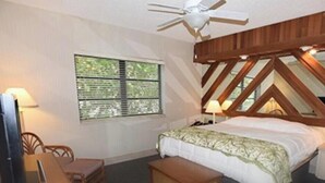Ein Schlafzimmer mit einem Bett, einem Deckenventilator, einem Fenster und einem Nachttisch mit Lampe.