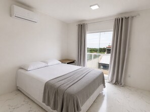 A bedroom with a bed, a nightstand, an air conditioning unit, and a window with curtains.