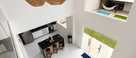 A modern interior with a kitchen, dining area, and a balcony with a pool.