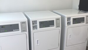 Tres lavadoras blancas, modernas y compactas con pantallas digitales, dispuestas en fila frente a una pared lisa.