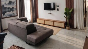 Una sala moderna con un sofá modular, un televisor de pantalla plana, decoración en la pared y un ventilador de techo.