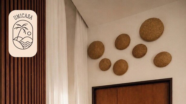 Una habitación con una puerta de madera, una planta en maceta y un muro con adornos circulares tejidos.