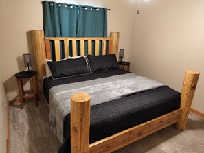 A bed with a wooden frame, a grey and black blanket, and two bedside tables with lamps. - Cozy Cottage 5-bedrooms, Ideal Beach Resort access, view of Bear Lake, sleeps 16 (Garden City)