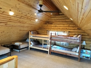 L’intérieur d’une cabane en bois, avec des lits superposés, une petite table et une lampe.