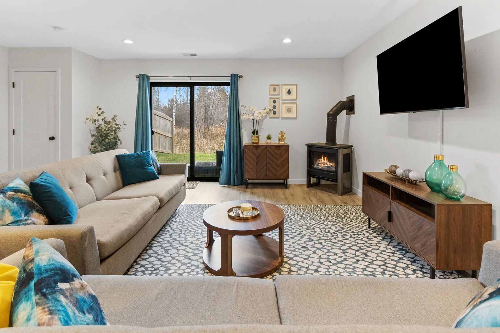Una sala de estar con sofá, mesa de centro, chimenea, televisor y vista a través del ventanal.