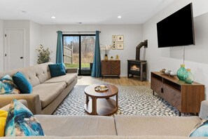Una sala de estar con sofá, mesa de centro, chimenea, televisor y vista a través del ventanal.