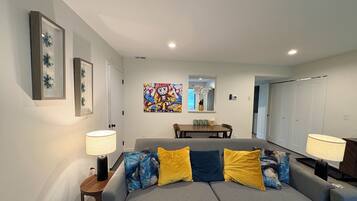A modern living room with a grey sofa, two lamps, a coffee table, and a colorful artwork on the wall.