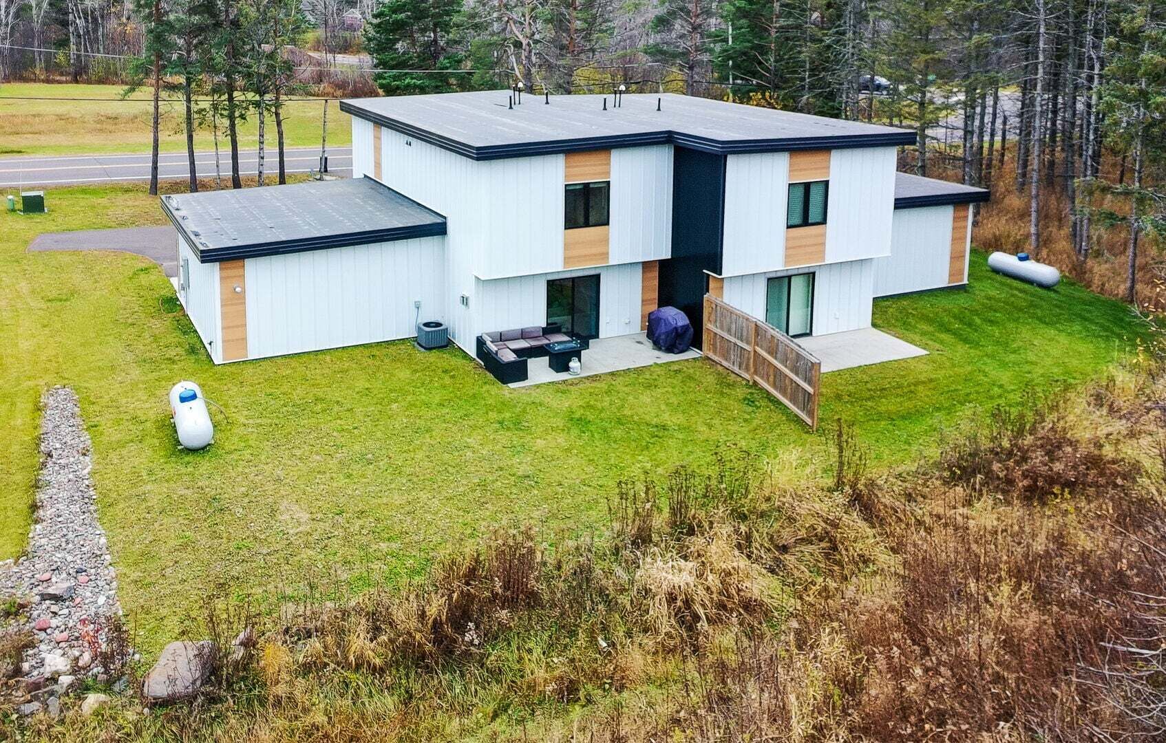 Ein modernes, zweistöckiges Haus mit flachem Dach, großen Fenstern und einer überdachten Sitzterrasse.