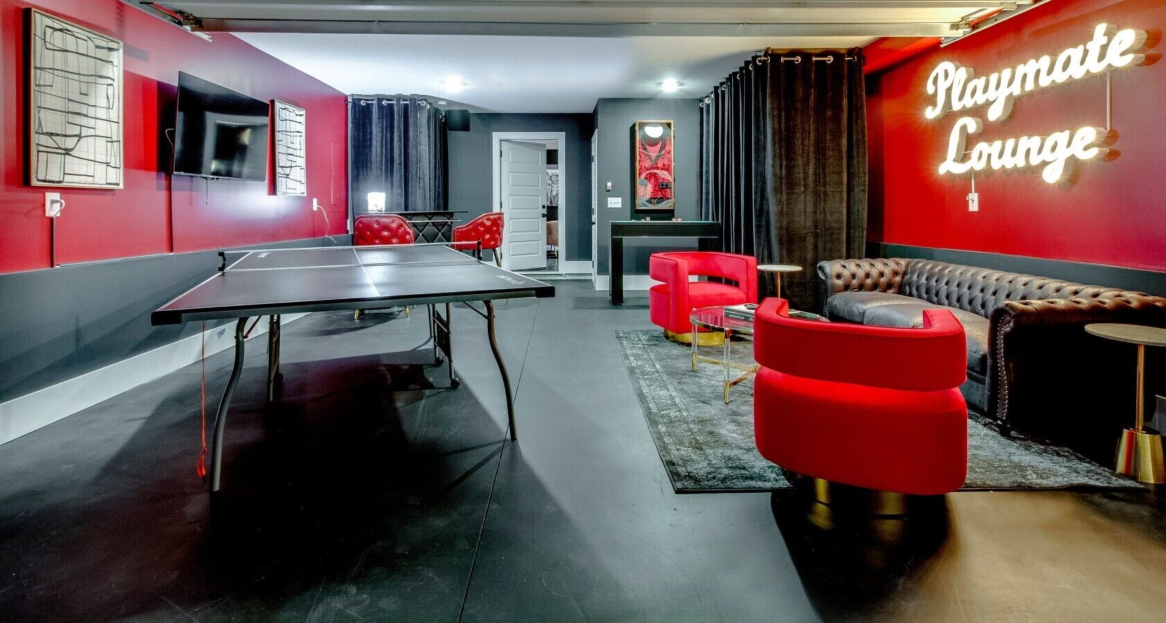A ping pong table, red chairs, a sofa, and a neon sign reading 'Playmate Lounge'.