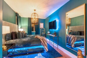 Stylish bedroom retreat featuring vibrant peacock-teal bedding, warm LED accent lighting, and dual vanity mirror. - The Playmate - a Glam Rooftop Retreat with Hot Tub, Putting Green & Skyline View (Nashville)