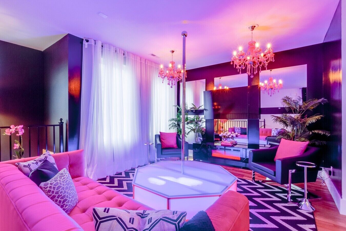 A modern living room with a pink sofa, a round coffee table, and a large mirror.