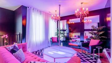 A modern living room with a pink sofa, a round coffee table, and a large mirror.