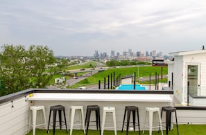 A rooftop bar with a city skyline view, multiple bar stools, and a sign indicating free speech. - The Playmate - a Glam Rooftop Retreat with Hot Tub, Putting Green & Skyline View (Nashville)