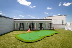 Um campo de mini golfe com grama sintética, bandeiras e banquetes dispostos ao redor.