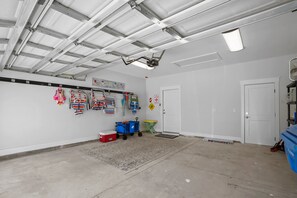 A spacious indoor area with a high ceiling, a white door, and a blue storage unit. - Caribbean Surf | Private Heatable Pool | Beach Access | PCB | Near Beach (Panama City Beach)