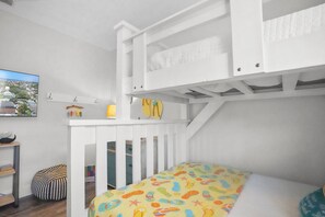 A child's bunk bed with a colorful mattress, a small desk with a chair, and a hanging toy. - Caribbean Surf | Private Heatable Pool | Beach Access | PCB | Near Beach (Panama City Beach)