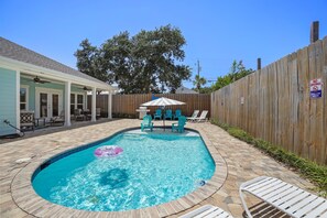 Ein Garten mit Swimmingpool, Liegestühlen und Holzzaun.