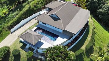 A modern house with a swimming pool, a covered patio, and a well-maintained lawn.