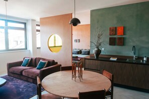 Ein moderner Wohnraum mit einem runden Esstisch, einer Couch und einer Küchenzeile.