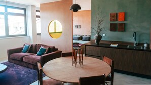 Un moderno salón con una mesa redonda, sofá y una zona de cocina con fregadero y armarios.