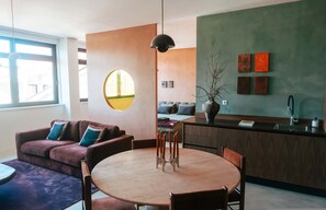 Ein modernes Wohnzimmer mit rundem Tisch, einer Couch und einer Küchenzeile mit Spüle und Schränken.