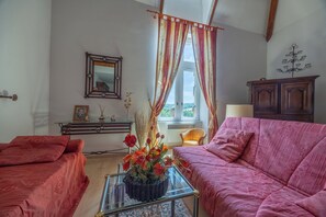A room with a bed, a sofa, a mirror, a dresser, and a window with curtains. - Duplex de charme dans château de Beuzeval - Welkeys (Houlgate)