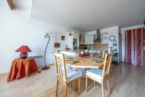 A dining area with a wooden table, chairs, and a red tablecloth. - Duplex de charme dans château de Beuzeval - Welkeys (Houlgate)