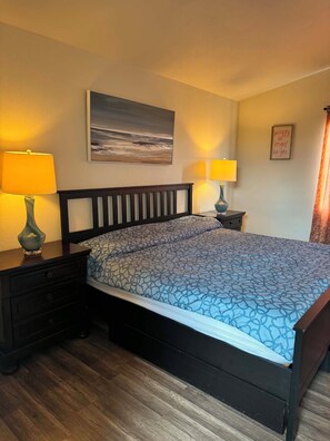 A hotel room with a bed, two bedside tables, a nightstand, a lamp, a painting, and a decorative sign. - Serene 4-bedroom house in San Diego perfect for your getaway (San Diego)