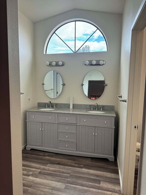 A bathroom with a vanity, two mirrors, a window, and a door. - Serene 4-bedroom house in San Diego perfect for your getaway (San Diego)
