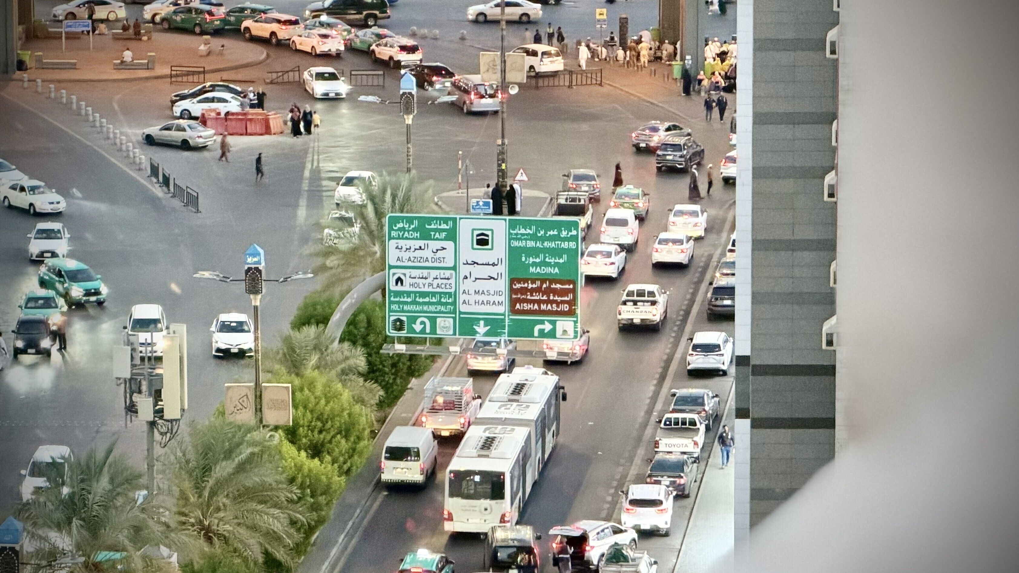 Une intersection urbaine très fréquentée, avec plusieurs voies de circulation et des panneaux de signalisation.