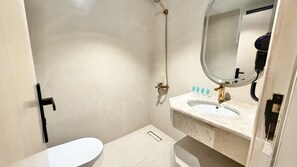 Een badkamer met toilet, wastafel, spiegel en douche.