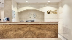 A reception desk with a marble counter and two wall clocks. - Al Jazeerah Hotel (Makkah)