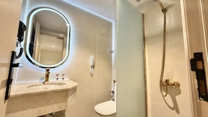A bathroom with a marble sink, a toilet, a shower with a handheld showerhead, and a wall-mounted telephone. - Al Jazeerah Hotel (Makkah)